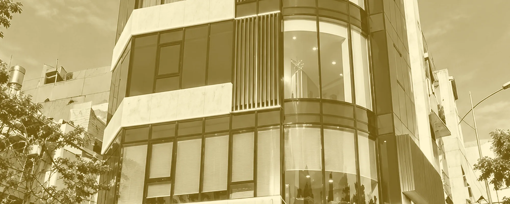 The curved glass frontage of the ANRICO HOLDINGS head office seen from below